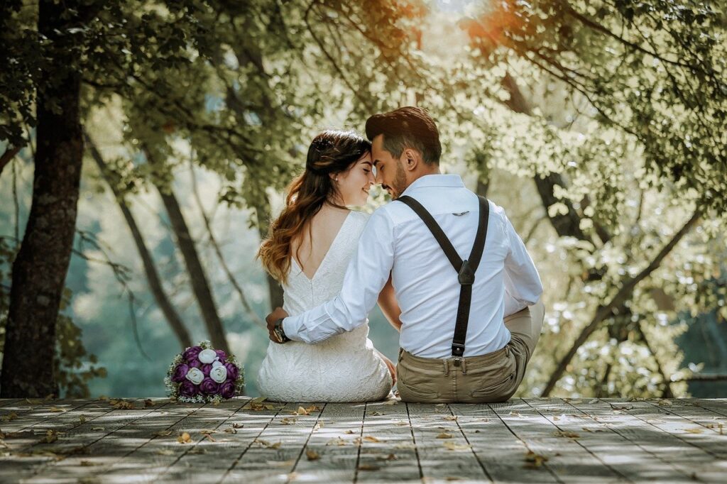 Ein paar sitzt romantisch in einem Wald: Euren Hochzeitsstil bei der Planung zu finden, ist besonders wichtig.